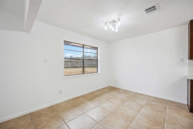 unfurnished room with a chandelier and light tile patterned floors