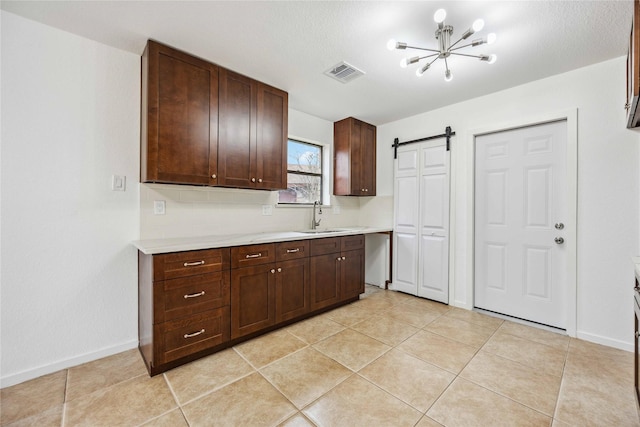 kitchen with light tile patterned flooring, a barn door, sink, and dark brown cabinetry