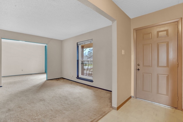 carpeted foyer entrance with a textured ceiling