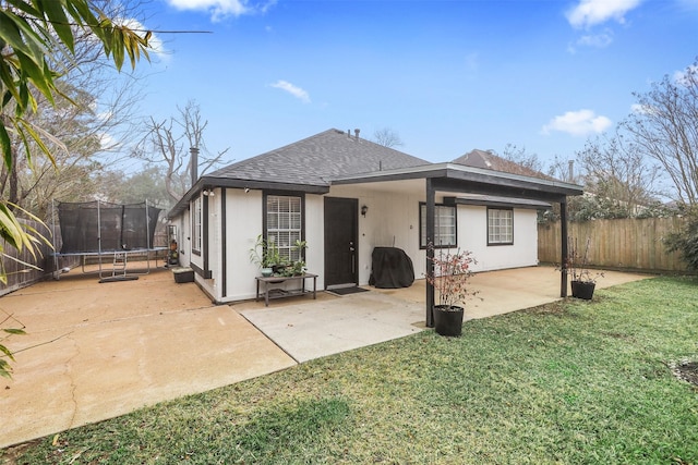 back of property with a patio, a yard, and a trampoline