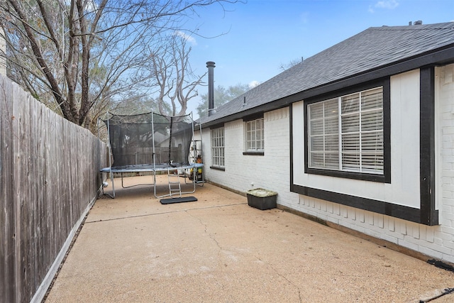 view of side of home with a patio and a trampoline