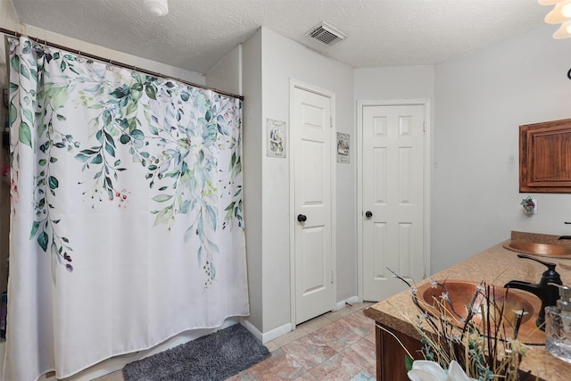 bathroom featuring vanity, curtained shower, and a textured ceiling