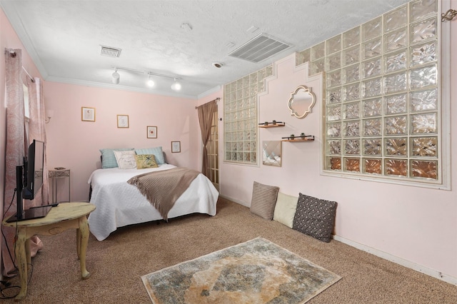 carpeted bedroom with ornamental molding, rail lighting, and a textured ceiling