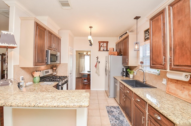 kitchen with appliances with stainless steel finishes, pendant lighting, sink, light stone counters, and kitchen peninsula