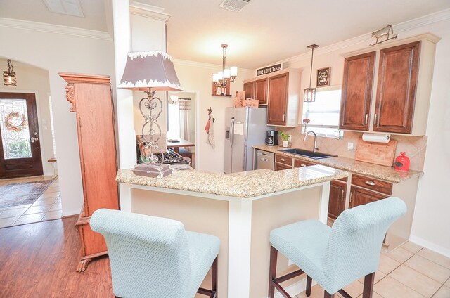 kitchen featuring appliances with stainless steel finishes, sink, a kitchen bar, hanging light fixtures, and kitchen peninsula