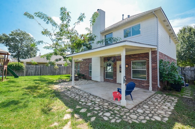 back of property with a playground, a yard, and a patio area