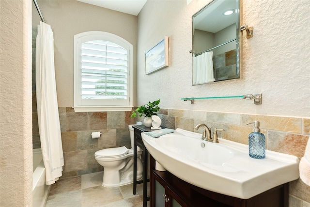 full bathroom with shower / bath combo, sink, tile walls, and toilet