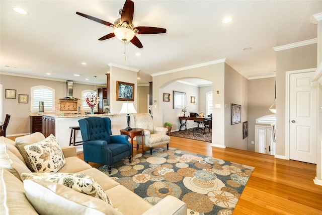 living room with ceiling fan, ornamental molding, and light hardwood / wood-style flooring