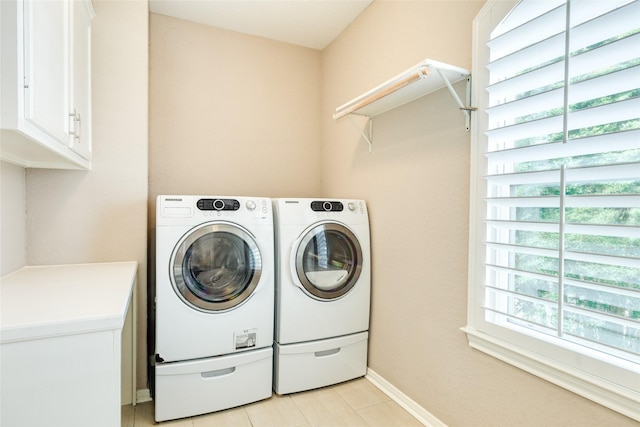 washroom featuring cabinets, washing machine and dryer, a wealth of natural light, and light tile patterned flooring