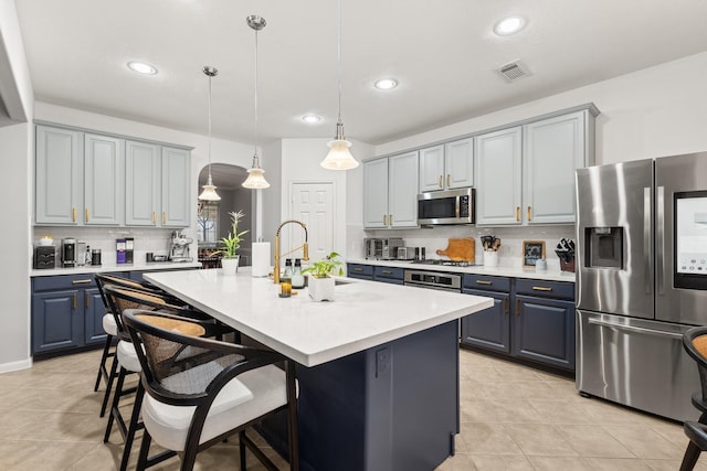 kitchen featuring pendant lighting, sink, a breakfast bar area, appliances with stainless steel finishes, and a center island with sink