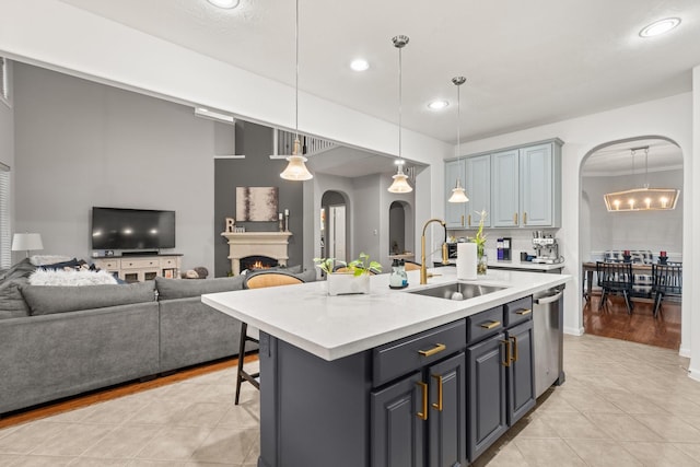 kitchen featuring light tile patterned flooring, sink, dishwasher, an island with sink, and pendant lighting