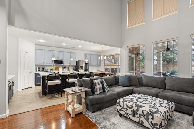 living room featuring a towering ceiling, light hardwood / wood-style floors, and a notable chandelier