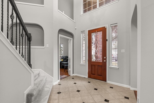 entrance foyer with a towering ceiling and light tile patterned floors