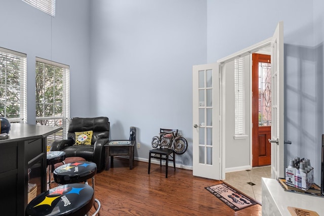 living area featuring hardwood / wood-style floors, french doors, and a high ceiling