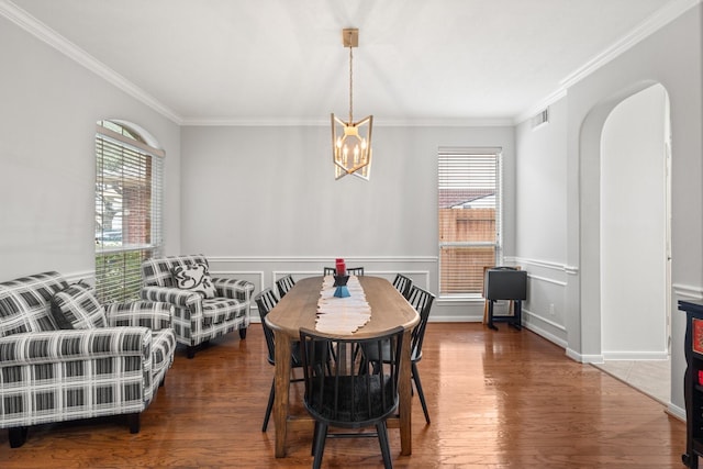 dining area featuring dark wood-type flooring, a healthy amount of sunlight, crown molding, and a chandelier