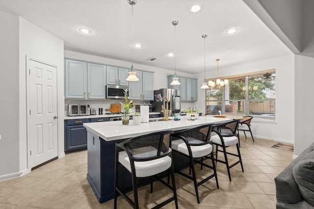 kitchen featuring pendant lighting, stainless steel appliances, a kitchen bar, and a center island with sink