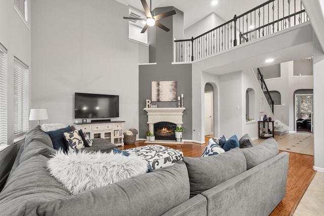 living room featuring a high ceiling, ceiling fan, and light hardwood / wood-style flooring