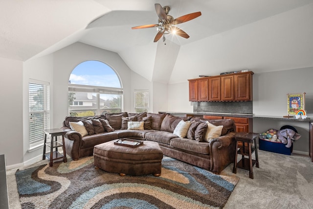 carpeted living room with ceiling fan and high vaulted ceiling