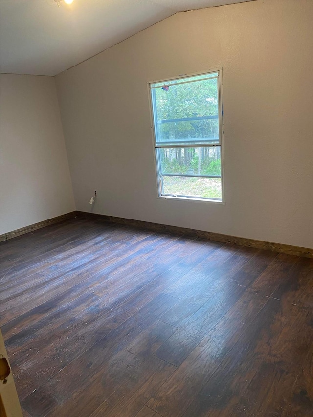 spare room with vaulted ceiling and dark hardwood / wood-style flooring