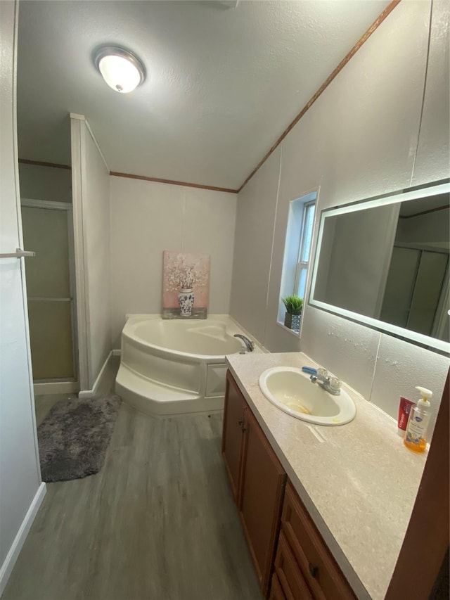 bathroom featuring crown molding, hardwood / wood-style flooring, vanity, vaulted ceiling, and independent shower and bath