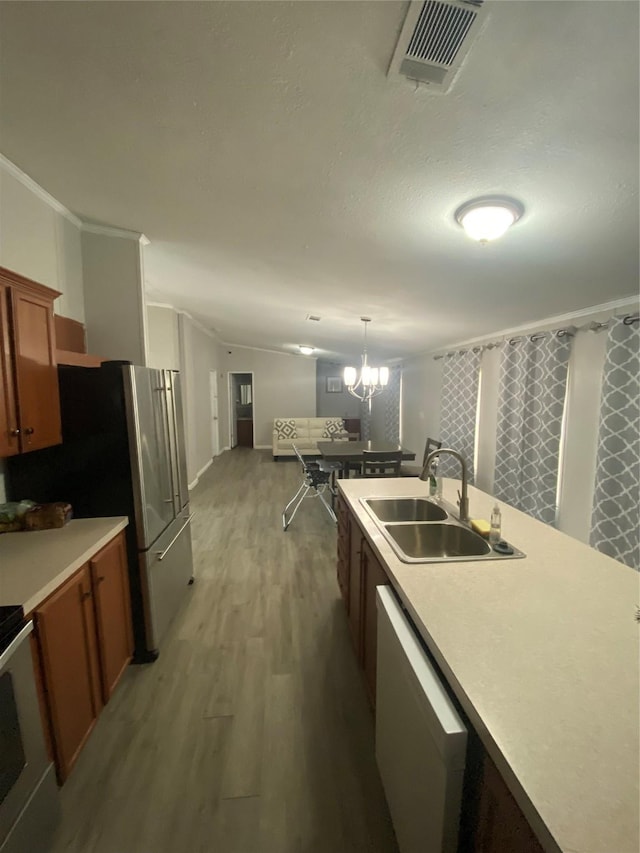 kitchen with pendant lighting, sink, dishwashing machine, a chandelier, and light hardwood / wood-style floors