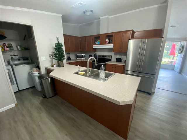 kitchen with appliances with stainless steel finishes, wood-type flooring, sink, washing machine and clothes dryer, and crown molding