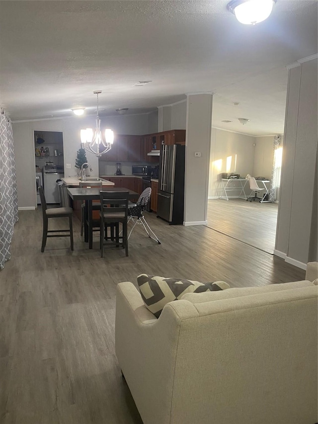 living room featuring wood-type flooring, sink, and a notable chandelier