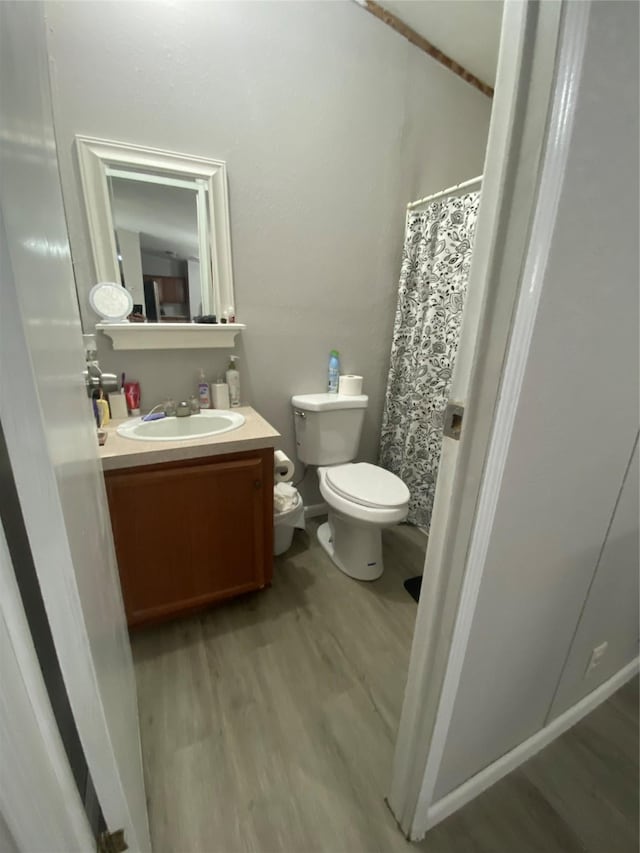 bathroom featuring walk in shower, wood-type flooring, toilet, and vanity