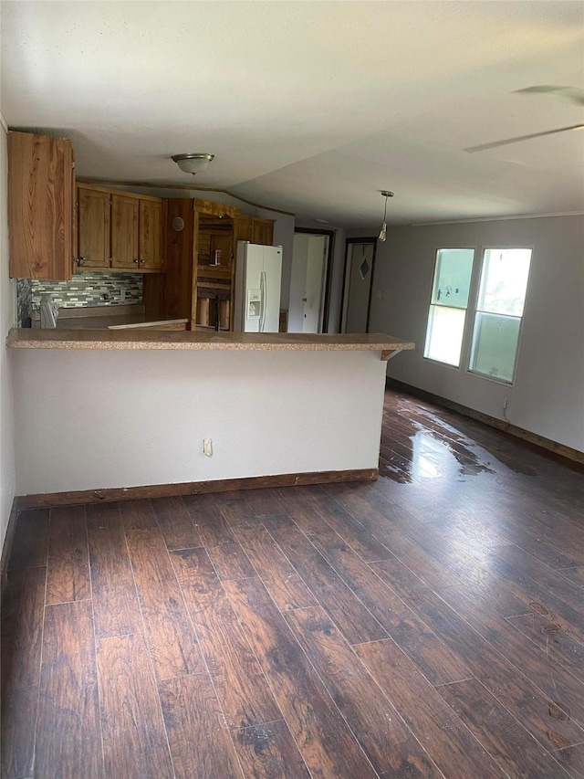 kitchen featuring dark wood-type flooring, decorative light fixtures, kitchen peninsula, and white fridge with ice dispenser