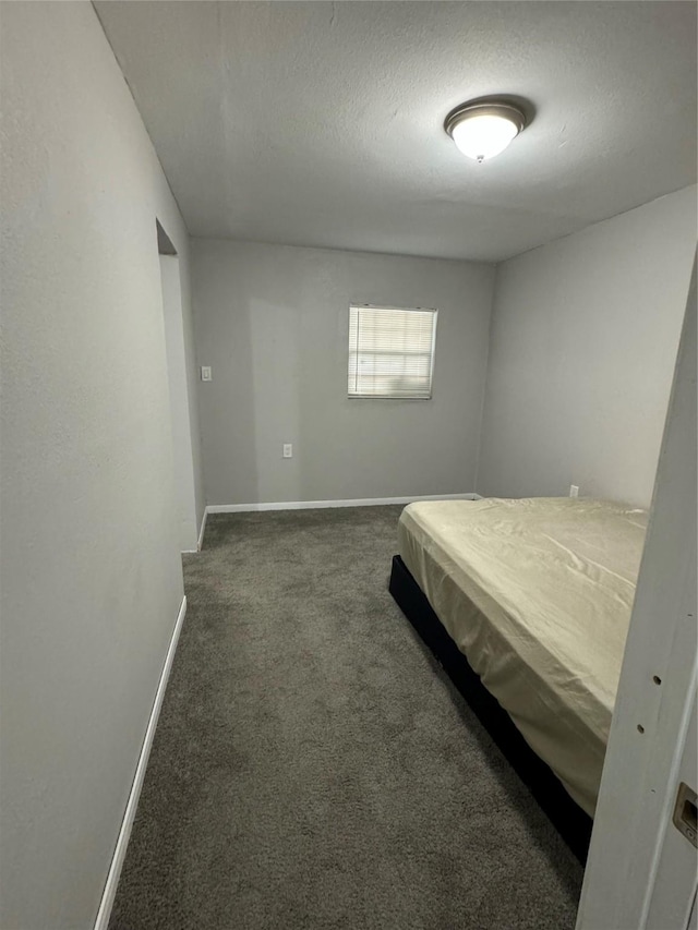 unfurnished bedroom with dark carpet and a textured ceiling