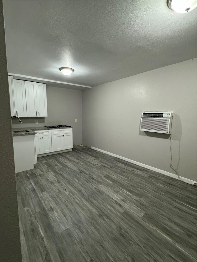 interior space with dark wood-type flooring, a wall unit AC, and a textured ceiling