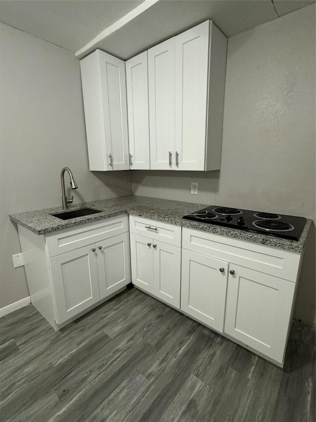 kitchen with sink, dark hardwood / wood-style floors, white cabinets, stone countertops, and black electric cooktop