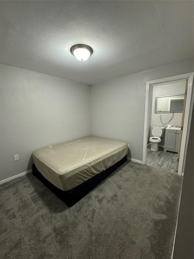 carpeted bedroom with a textured ceiling and ensuite bathroom