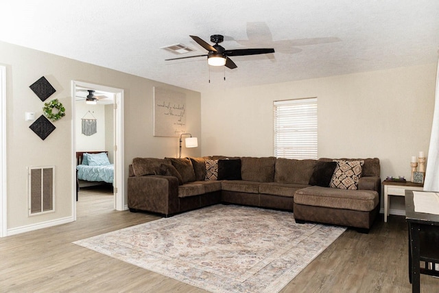 living room with ceiling fan, hardwood / wood-style floors, and a textured ceiling