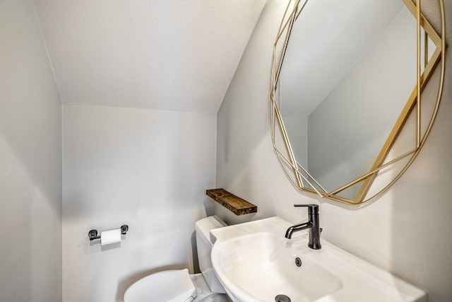 bathroom with lofted ceiling, sink, and toilet