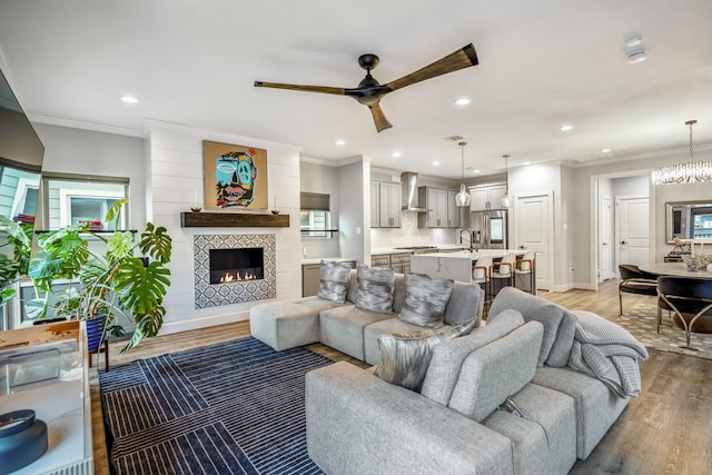 living room with a tiled fireplace, light hardwood / wood-style flooring, and ornamental molding