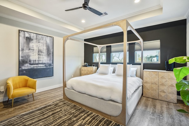 bedroom featuring crown molding, hardwood / wood-style flooring, a tray ceiling, and ceiling fan