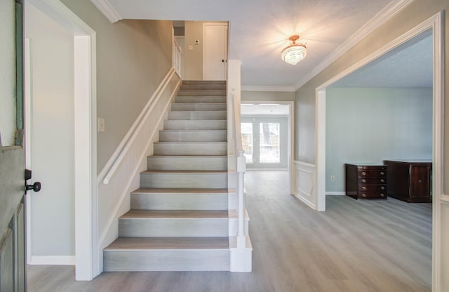 stairs featuring crown molding and wood-type flooring