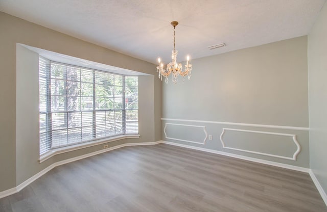 empty room with a notable chandelier and wood-type flooring