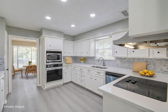 kitchen with sink, stainless steel appliances, tasteful backsplash, light hardwood / wood-style floors, and white cabinets