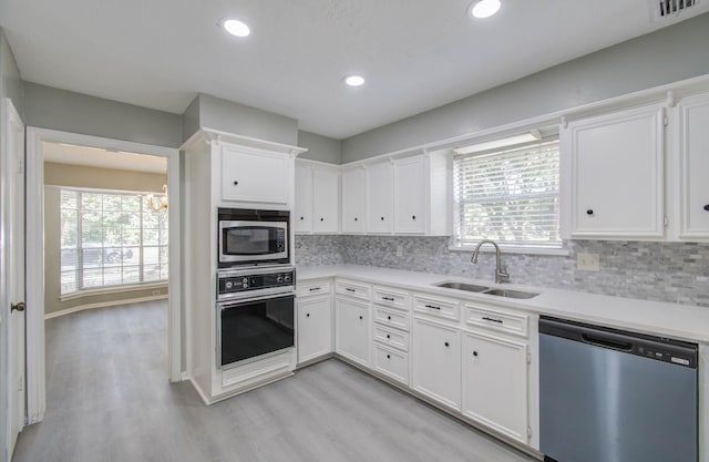 kitchen with light wood-type flooring, stainless steel appliances, sink, and white cabinets