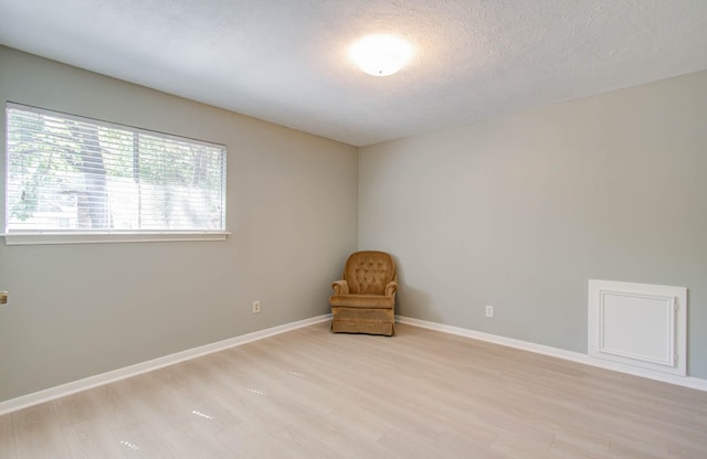 spare room featuring a textured ceiling and light hardwood / wood-style flooring