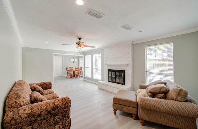 living room with crown molding, plenty of natural light, a fireplace, and light hardwood / wood-style floors