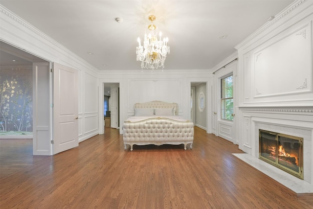 bedroom with crown molding, a fireplace, dark wood-type flooring, and a notable chandelier