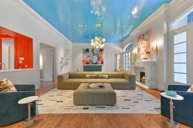 living room with a premium fireplace, a chandelier, crown molding, and light hardwood / wood-style flooring