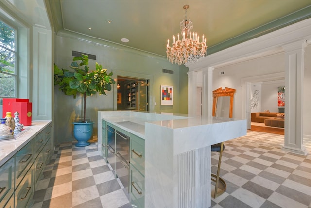 kitchen featuring ornate columns, a kitchen bar, hanging light fixtures, ornamental molding, and an inviting chandelier