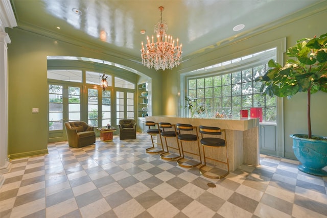 bar with an inviting chandelier, pendant lighting, and ornamental molding