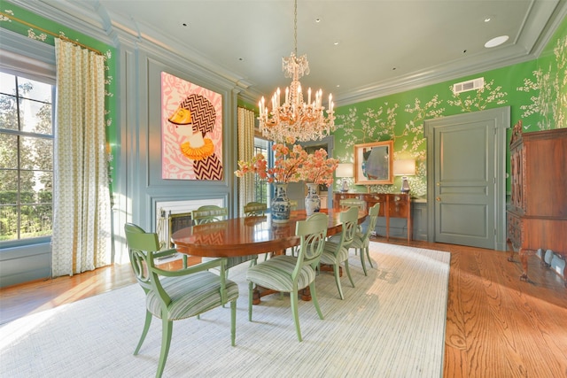 dining room with visible vents, wallpapered walls, ornamental molding, an inviting chandelier, and wood finished floors