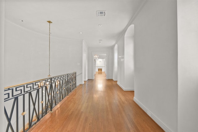 hallway featuring ornamental molding, a notable chandelier, and light hardwood / wood-style floors