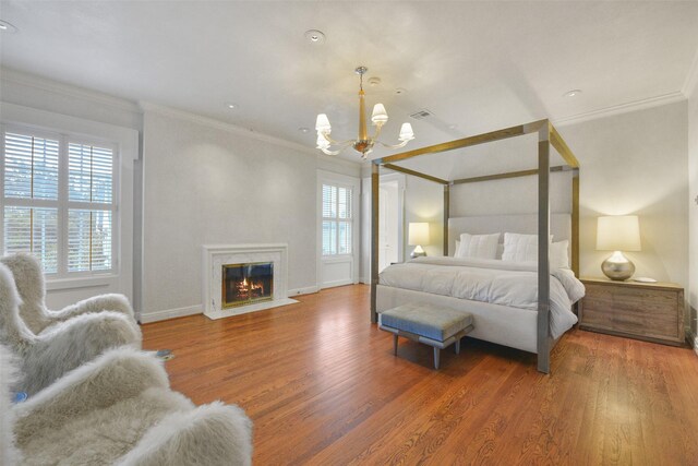 bedroom featuring an inviting chandelier, a high end fireplace, dark wood-type flooring, and ornamental molding